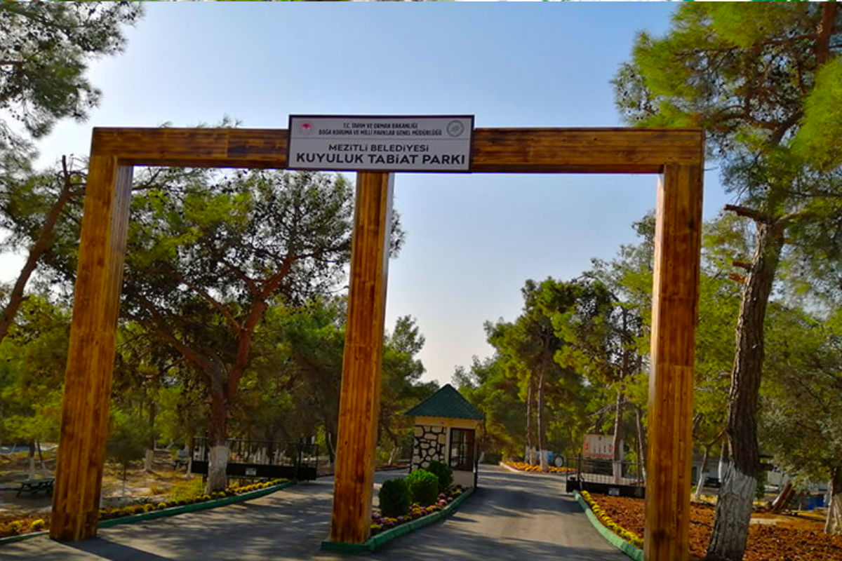 Eingangstor des Kuyuluk Nature Park in Mezitli, umgeben von Bäumen